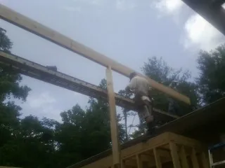 Carpenter setting a ridge beam over a new addition frame — Ice Dam Removal by Roofing Brothers in Minotola