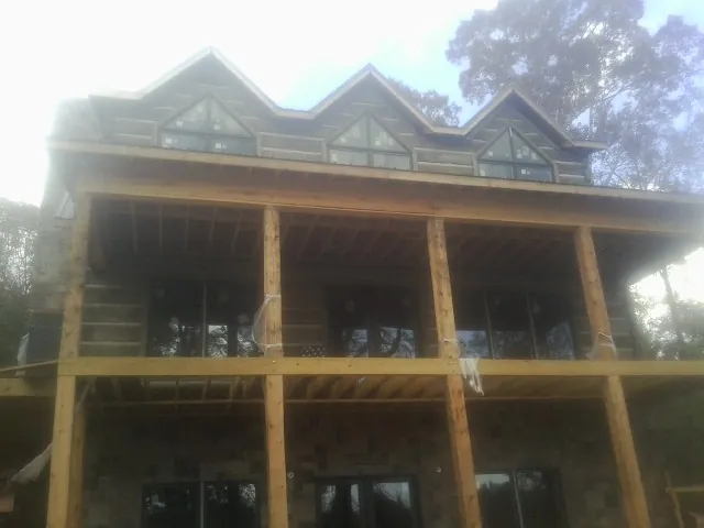 Dormers and porch framing on a large log home under construction — Roof Coating work by our crew in Minotola