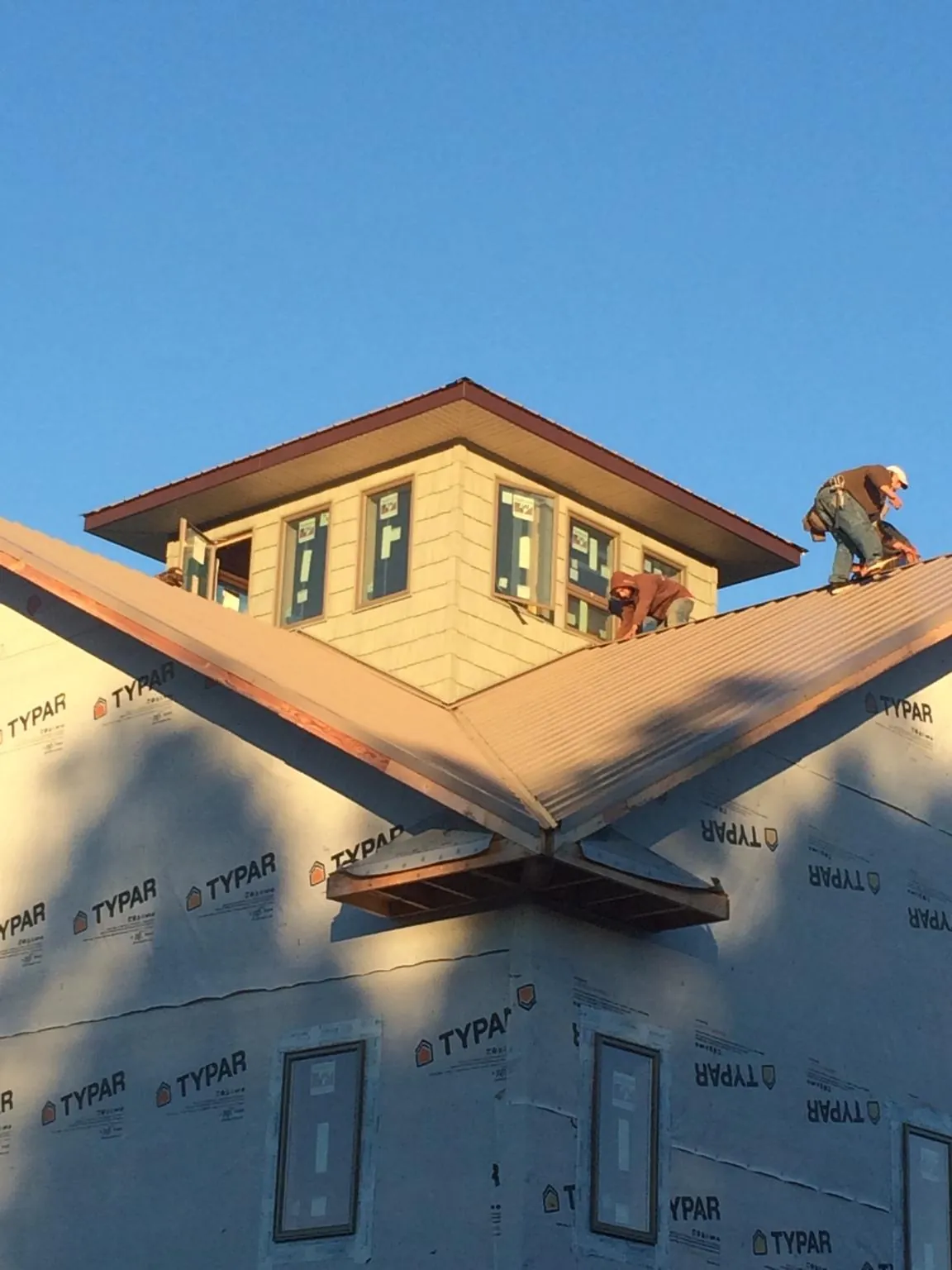 Roofers working around a rooftop cupola on a new metal roof at sunset — Roof Waterproofing in Minotola by Roofing Brothers